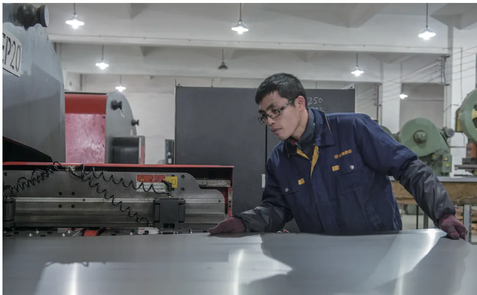 Grantec worker loading a sheet of cold-rolled steel into a CNC machine
